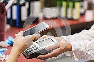 The buyer pays for the item at the cash register using a smartphone. Contactless payment process in the supermarket