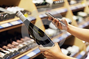 Buyer photographs a bottle of wine, a mystery shopper. Checking the quality of the goods by barcode