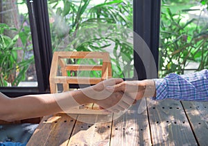 Buyer and seller shacking hand after contract signature, coins in wooden house. Loans for real estate concept
