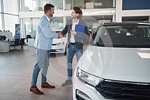 Buyer shaking hand with salesman in car sales salon