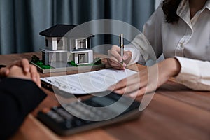 Buyer signs the loan contract paper with a pen on the desk. Enthusiastic