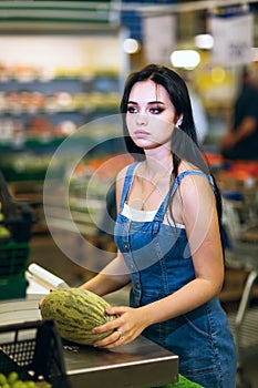 Buyer weighs melon on electronic scales in a supermarket