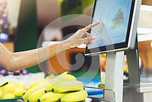 The buyer weighs the yellow bananas and points the fingers on the screen electronic scales, woman shopping healthy food