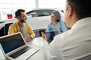 Buyers finalize a deal in office area of car dealership