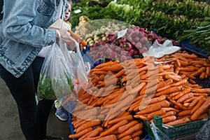 Buying fresh organic produce at the farmers& x27; market. A woman chooses fresh herbs, vegetables and fruits at a food
