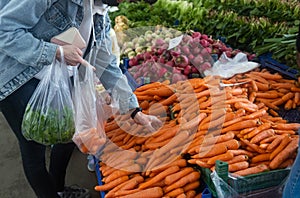 Buying fresh organic produce at the farmers& x27; market. A woman chooses fresh herbs, vegetables and fruits at a food