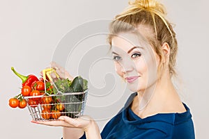 Woman holds shopping basket with vegetables