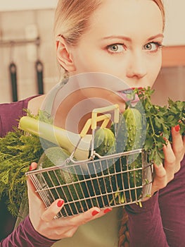 Woman in kitchen having vegetables holding shopping basket