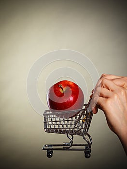 Woman holding shopping cart with apple inside