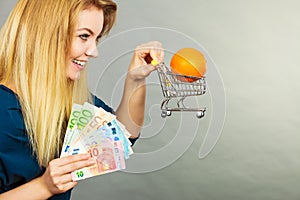 Woman holding shopping cart with orange inside