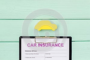 Buying new auto concept with insurance form and car toy on mint green wooden background top view copy space
