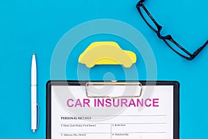 Buying new auto concept with insurance form, glasses and car toy on blue background top view