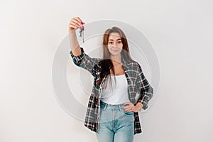 Buying and renting real estate. A pretty woman in a plaid shirt holds a bunch of keys. The hand with the keys in focus. White