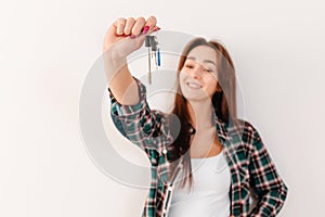 Buying and renting real estate. A smiling woman in a plaid shirt holds a bunch of keys. Hand with keys in focus, close