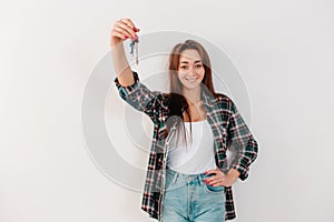 Buying and renting real estate. A smiling woman in a plaid shirt holds a bunch of keys. The hand with the keys in focus. White