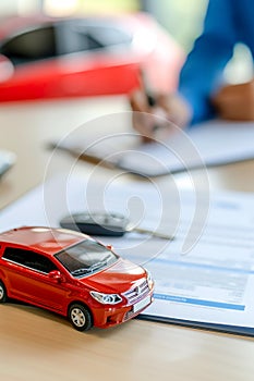 Buying, selling or renting car. Red car model and keys on the table, person signing insurance document or lease paper on