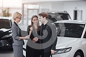 Buying their first car together. High angle view of young car salesman standing at the dealership telling about the