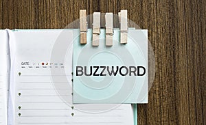 BUZZWORD notes paper and a clothes pegs on wooden background