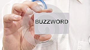 Buzzword word on the card in a man's hand on the background of a white shirt