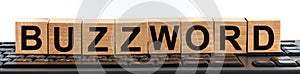 BUZZWORD word made with building blocks. A row of wooden cubes with a word written in black font is located on a black