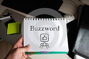 Buzzword word on notebook holding man against desktop