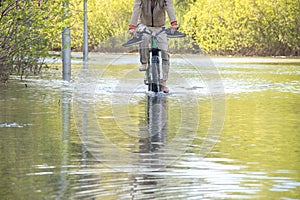 Bycyclist with naked feet try to overcome water during a flood in springtime