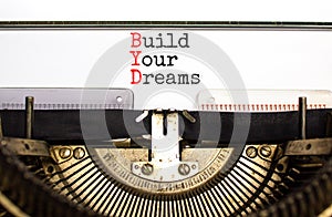 BYD build your dreams symbol. Concept words BYD build your dreams typed on retro old typewriter on a beautiful white paper