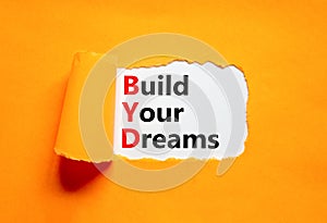 BYD build your dreams symbol. Concept words BYD build your dreams on white paper on a beautiful orange background. Business and