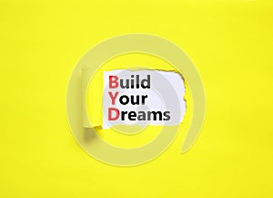 BYD build your dreams symbol. Concept words BYD build your dreams on white paper on a beautiful yellow background. Business and