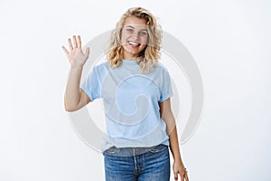 Bye see ya. Portrait of cute friendly and positive nice girl with blond hair and blue eyes smiling pleasant as waving