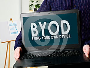 BYOD bring your own device. Man holds a laptop in his hands. photo