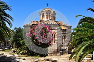 Byzantine Church of the Holy Apostles in Athens in the summer surrounded by plants against the blue sky.