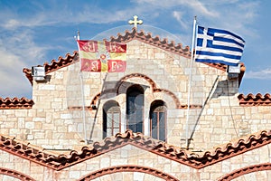 Byzantine and Greek flags are waving in front of the Holy Church of Saints Apostles Peter and Paul in Hymettos municipality-Athens