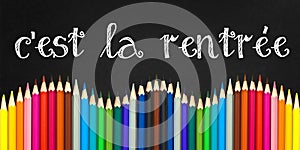 C`est la rentree meaning Back to school written on a black board background with a wave of colorful wooden pencils photo