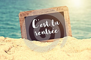 C`est la rentrÃÂ©e meaning Back to school written on a vintage chalkboard in the sand of a beach photo