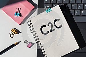 C2C abbreviation - consumer to consumer written on a notepad on background of office desk with pink paper notes, black pen, paper