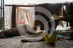 Ca Mau, Vietnam - Dec 6, 2016: Fisher family with the daughter playing near her mother mending casting net in Ngoc Hien, Ca Mau di