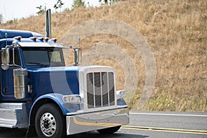 Cab of big rig blue bonnet semi truck driving on the road with h