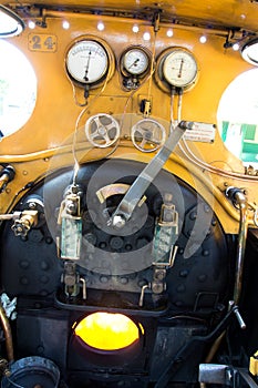 The cab or footplate of an old steam locomotive showing the controls and the burning fire