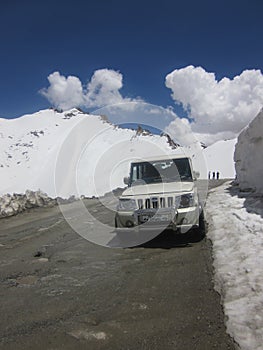 a cab on highway road passing through the hills and snow covered peaks in Leh, India