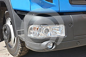 Cab, wheel and front black bumper with headlights, parking sensors and anti-fog lights of a blue truck