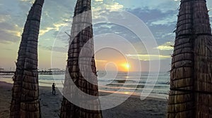 `Caballitos de totora` and pier at sunset on Huanchaco beach.