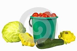 Cabbage, bucket with tomatoes, zucchini and squash on a white ba