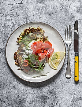 Cabbage fritters with smoked salmon and greek yogurt sauce on a grey background, top view. Delicious breakfast, tapas, appetizers