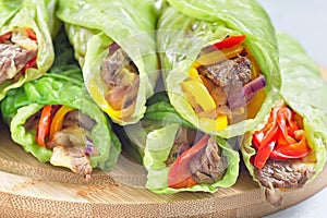 Cabbage leaves wraps with beef, vegetables and cheese, on a round wooden board, horizontal closeup