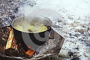 Cabbage with meat cooking in a cauldron on open fire during a festival