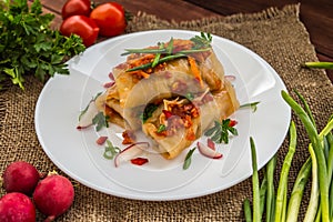 Cabbage rolls in tomato sauce. white plate. wood background.