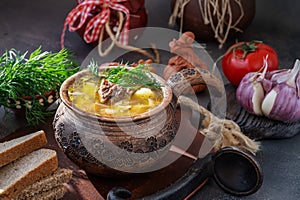 cabbage soup in a clay pot. Traditional Russian soup of sauerkraut and white cabbage, meat and potatoes in a clay pot