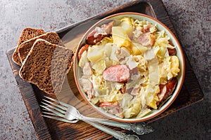 Cabbage stewed with potatoes, sausage, bacon and onions close-up in a bowl. Horizontal top view