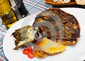 Cabeza de cordero - spanish dish. Lamb head with artichoke, tomatoes and potatoes photo